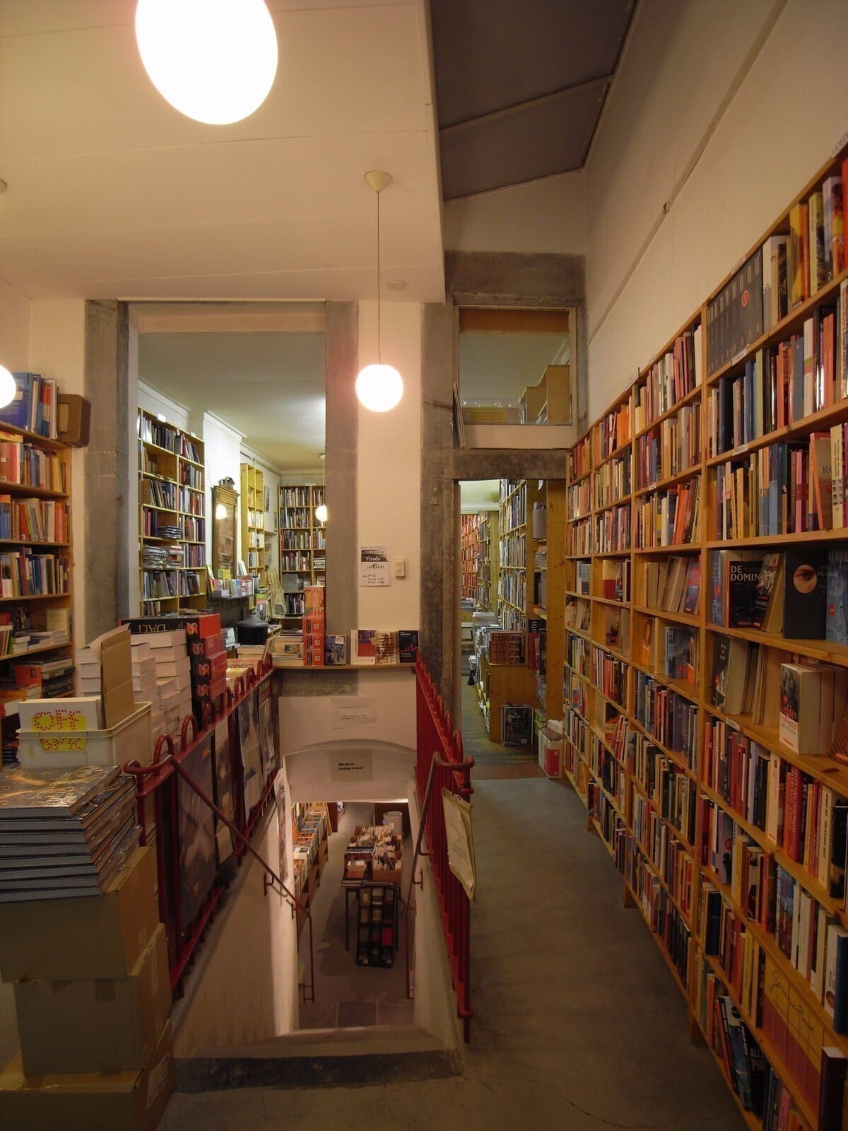 Gang met boekenkasten tot aan het plafond en een trap naar de ruimte eronder.