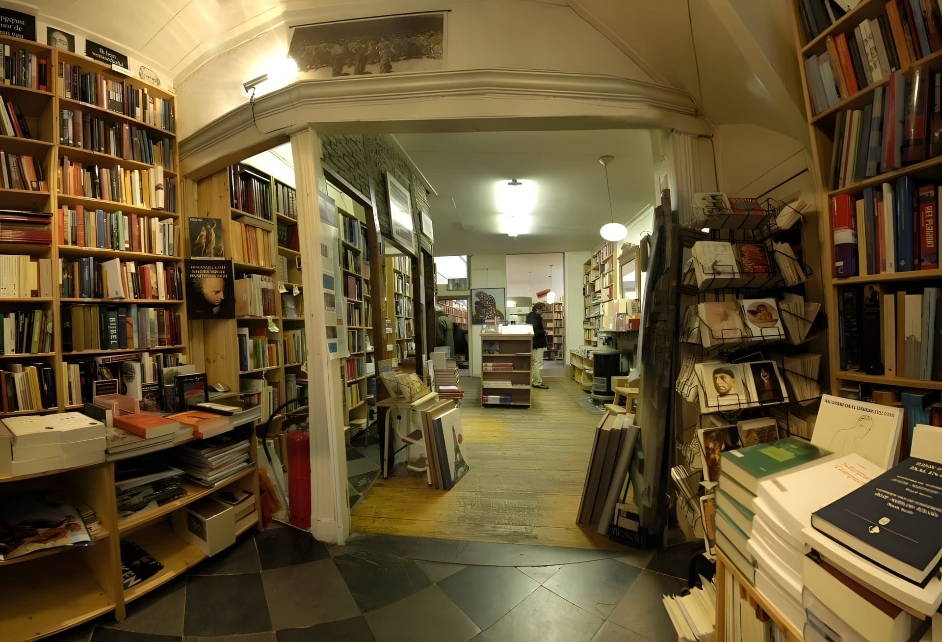 Blik door de boekhandel met houten kasten tot aan het plafond en een doorgang naar de volgende ruimte.