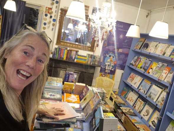 In de kinderboekenruimte, met prentenboeken op de tafel en in de blauwe kasten.
